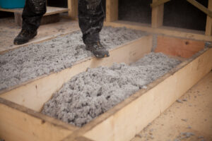 an installer inspects blown-in insulation in an attic.